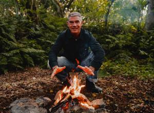 Richard Good warming his hands on campfire