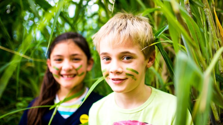 School children with face paints coming through leaves
