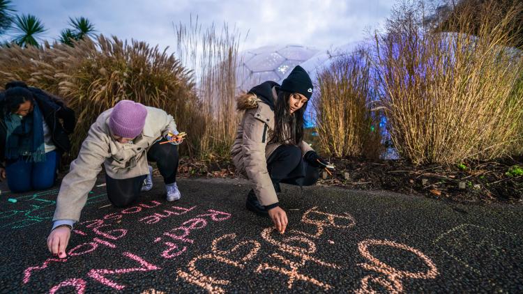 Teachers writing in chalk on the paths in front of Eden's Biomes