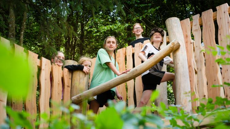 Children climbing on play equipment in the woods