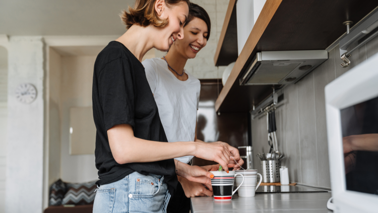 Two people making a cup of tea in a kitchen