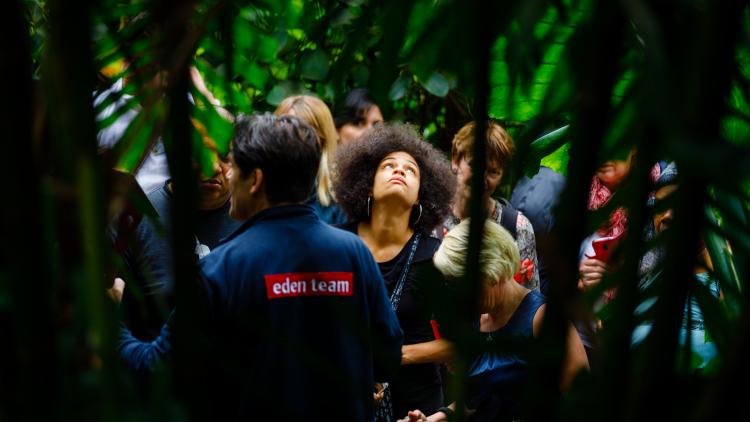 Woman looking up at plants as an Eden team member gives a tour 