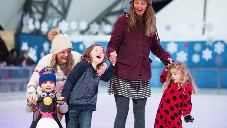 Mums and kids laughing as they ice skate