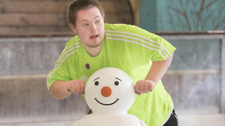 Teenager using snowman ice skating aid