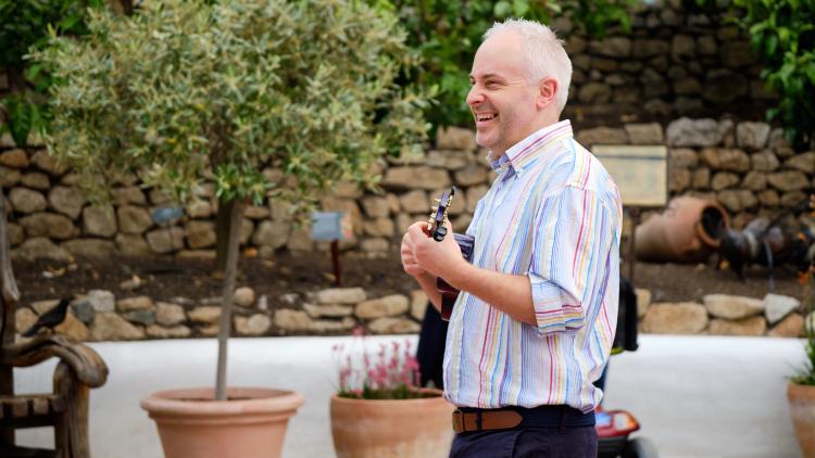 Man singing and playing a guitar in the Med Biome.