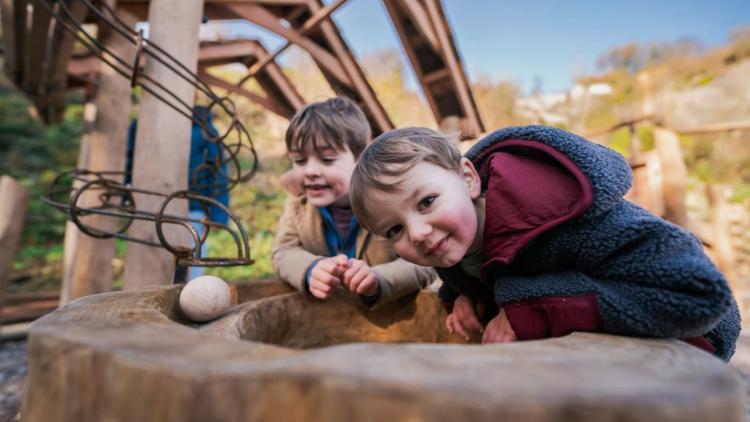 Two children leaning on giant marble run