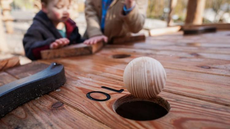 Two children throwing wooden marble on marble run