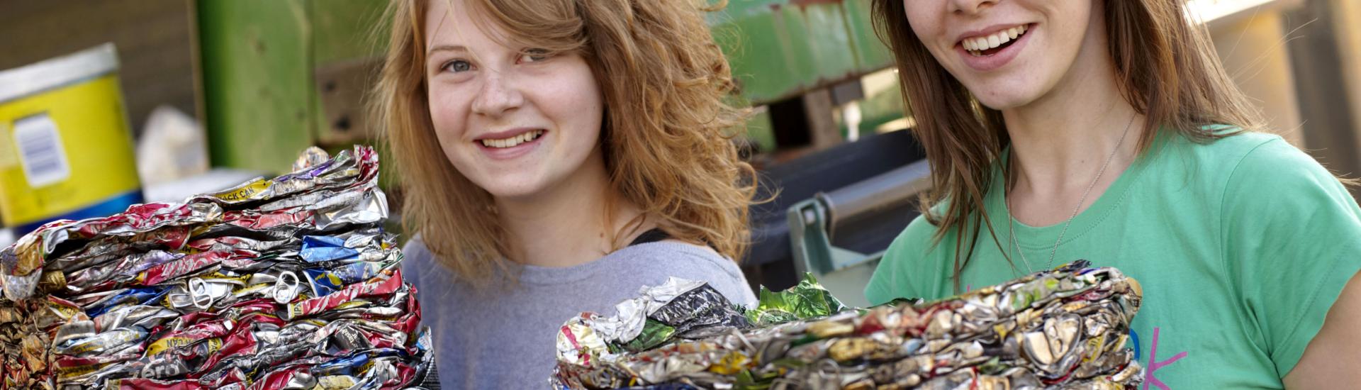 Two young girls standing next to each other and holding cubed crushed rubbish