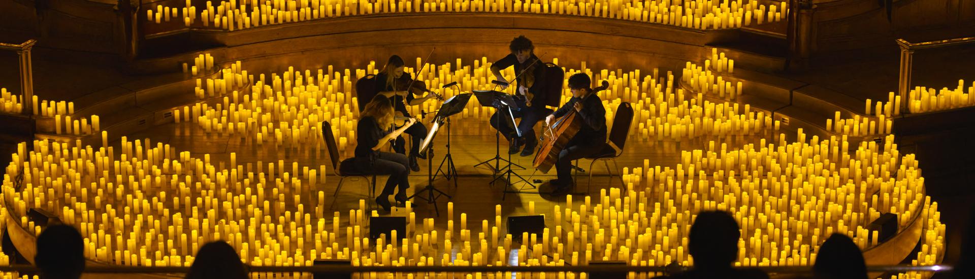 String quartet performing surrounded by thousands of candles