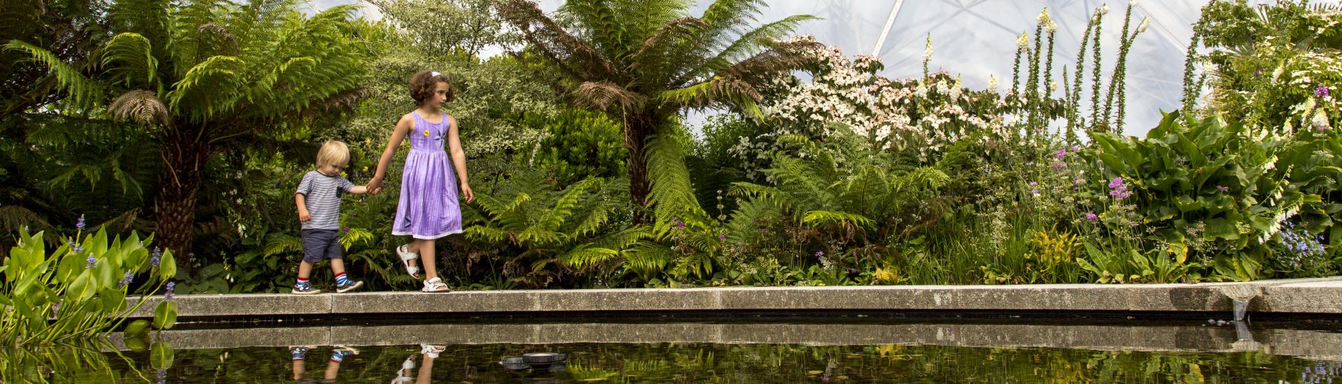 Two children exploring the Outdoor Gardens with Biome in background