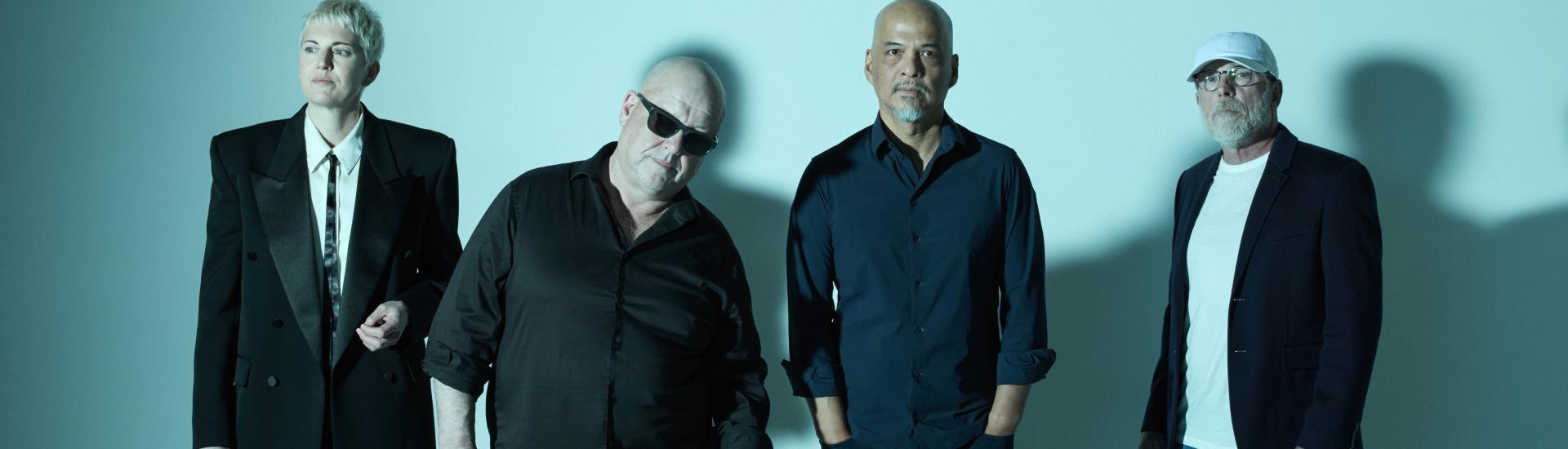 Pixies band standing against a duck egg blue backdrop