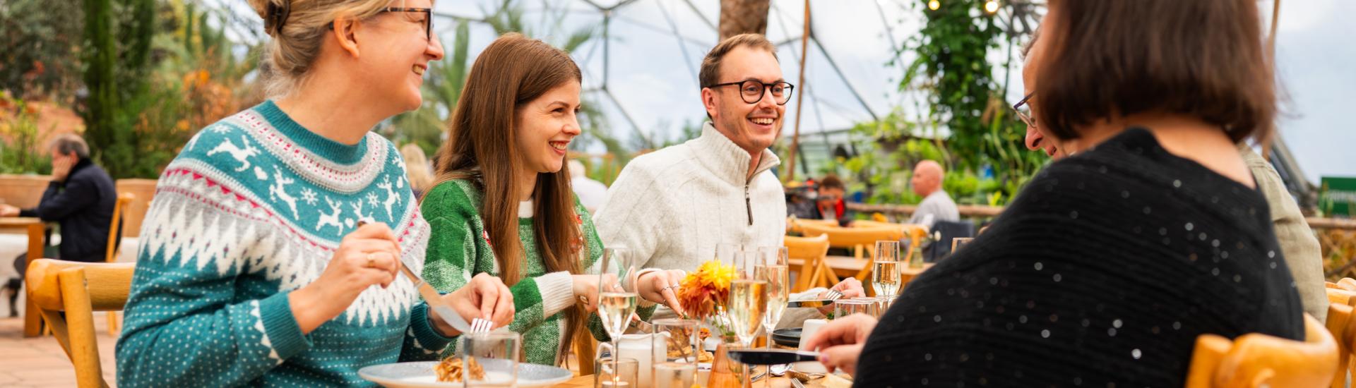 Group of people sat at table at Eden Project eating Mediterranean Biome Christmas lunch